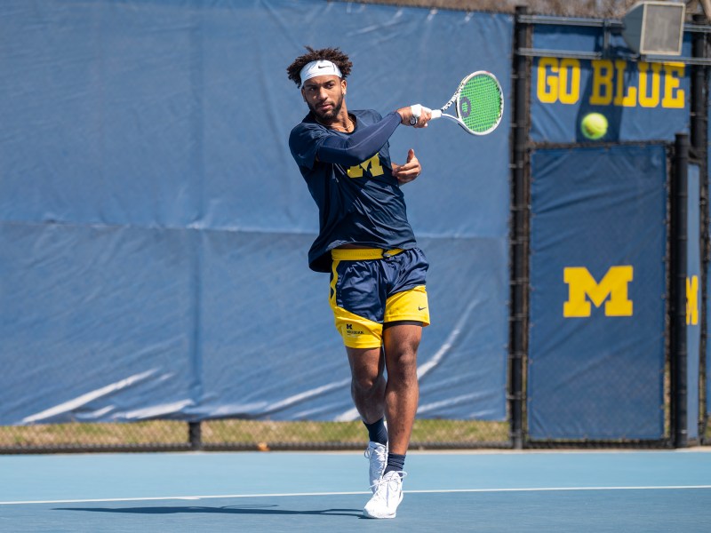 Tennis player Andrew Fenty picks the ball on the outdoor tennis courts.