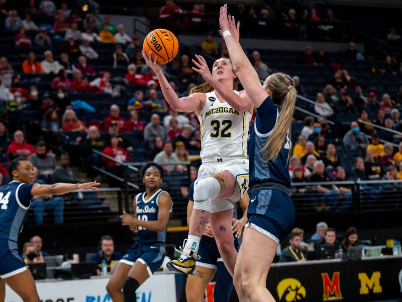 Leigha Brown is midair as she reaches up towards the basket for a layup as a Penn State player defends her at the Big Ten Tournament.