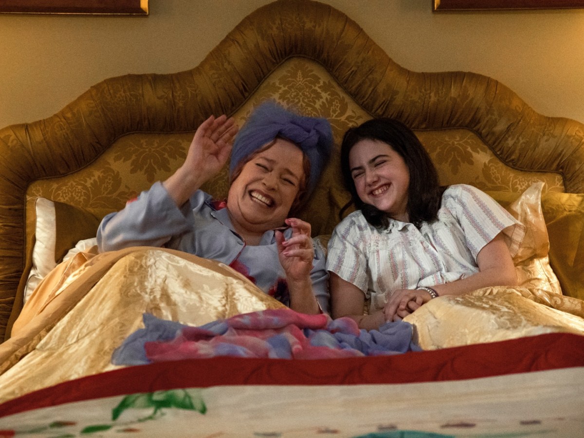 A woman and a girl in bed, smiling widely together.