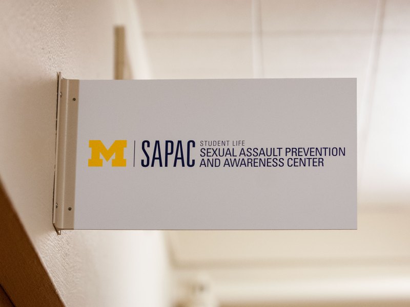 The white SAPAC sign reads "Student Life Sexual Assault Prevention and Awareness Center"
