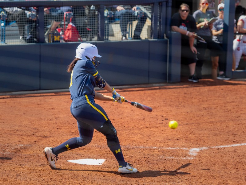 Lexie Blair swings at the ball. The ball is slightly in front of her and her arms are extended.
