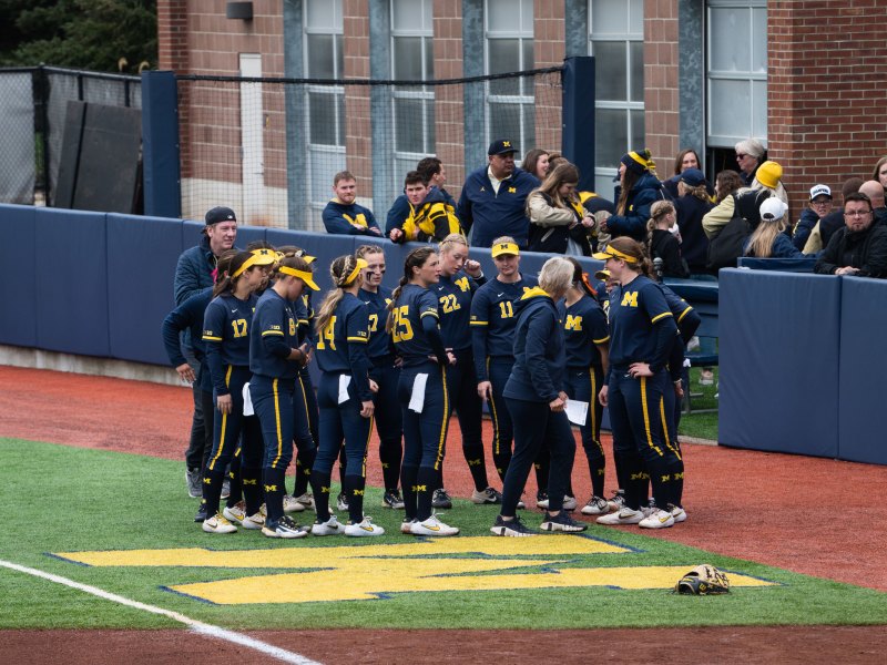 The University of Michigan softball team stand in a circle.