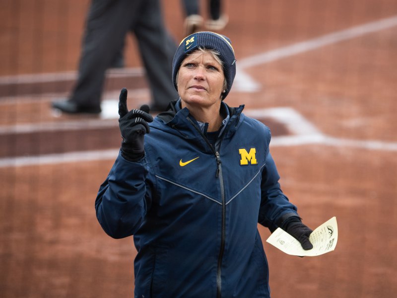 Head Coach Bonnie Tholl holds a piece of paper in her left hand and has her right pointer finger raised.