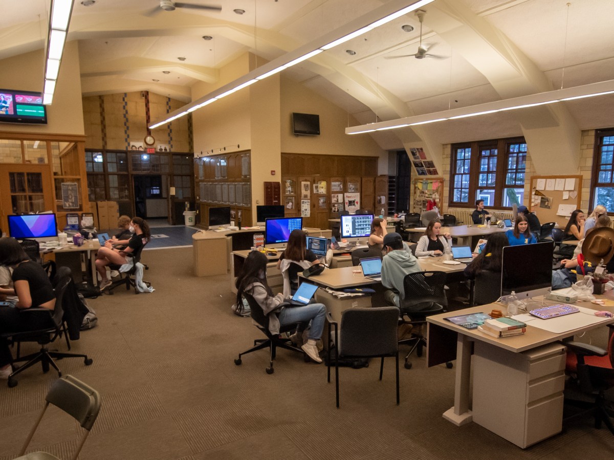 There are many students sitting in front of computers in the Michigan Daily newsroom.
