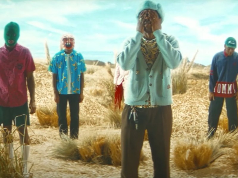 Tyler the Creator's four personas standing in a desert, the closest of which has his hands over his face.