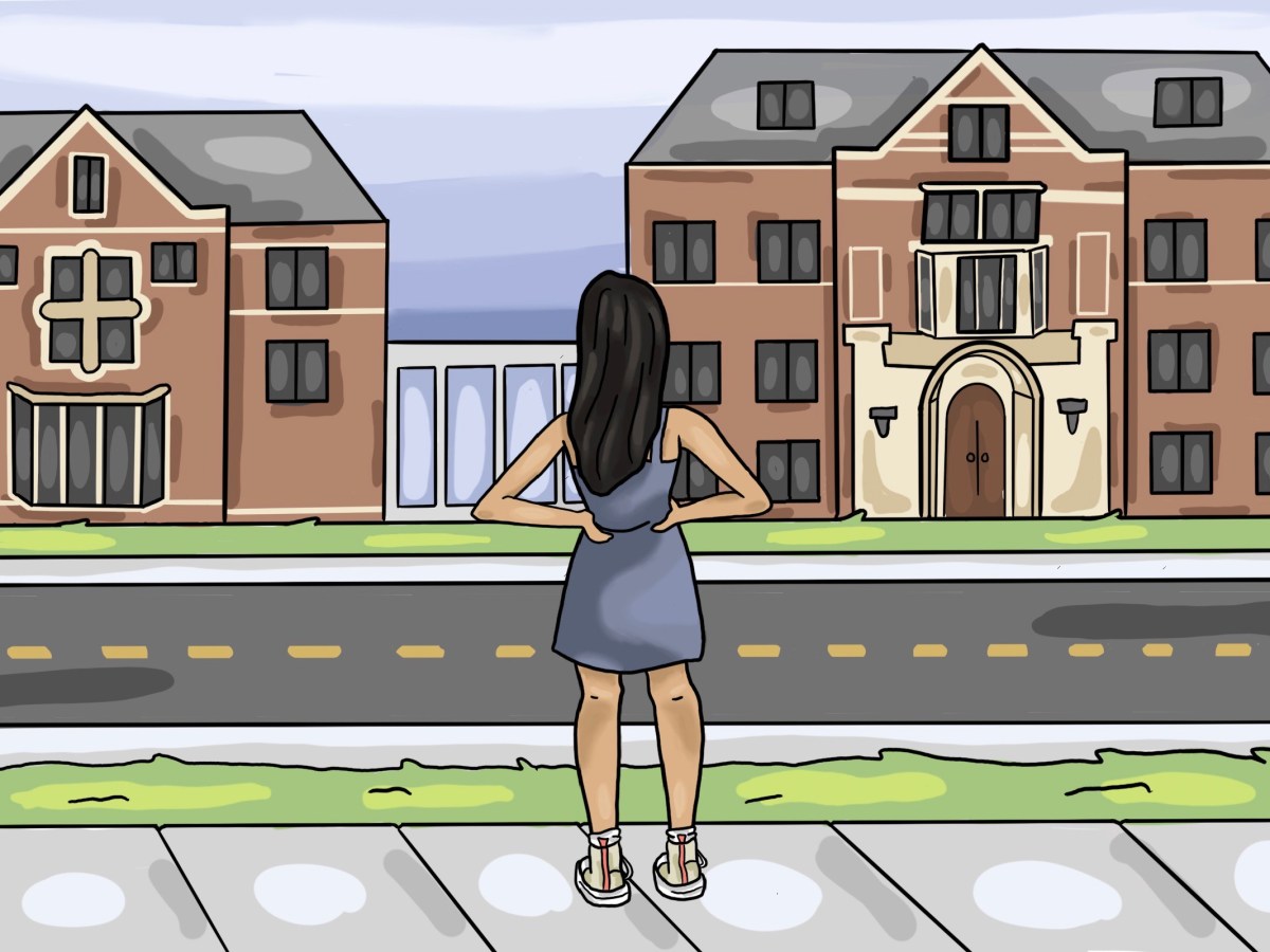 A girl standing on the sidewalk looking towards East Quad with her hands on her hips.