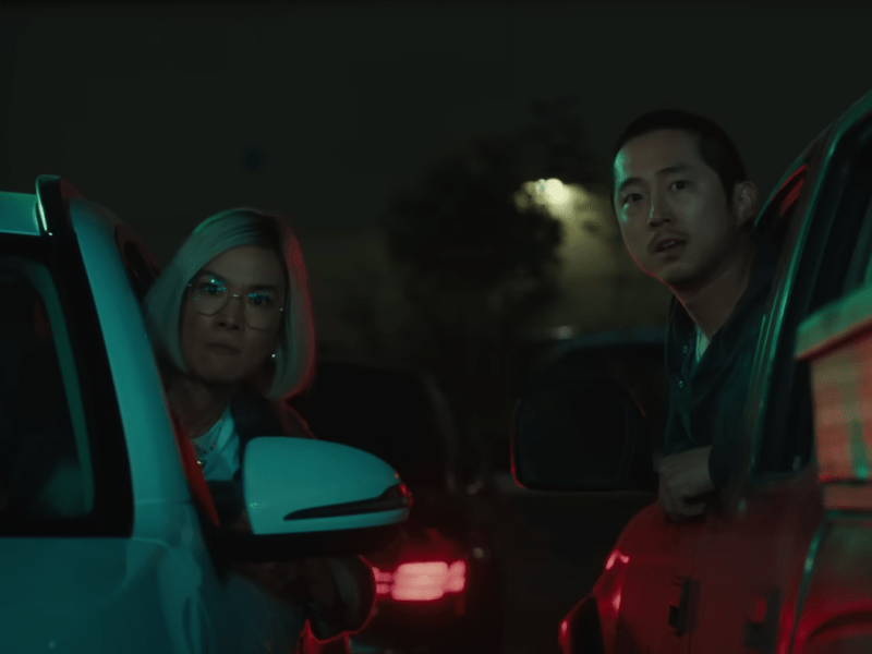 Screenshot from Netflix's Beef, featuring a man and a woman sticking their heads out of their respective car windows looking forwards towards us.
